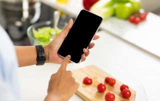 Black girl using smartphone with blank screen in the kitchen