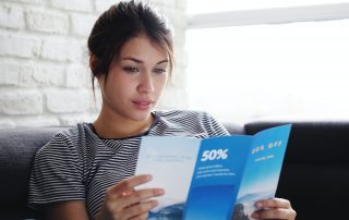 Woman Reading Travel Flye On Sofa At Home