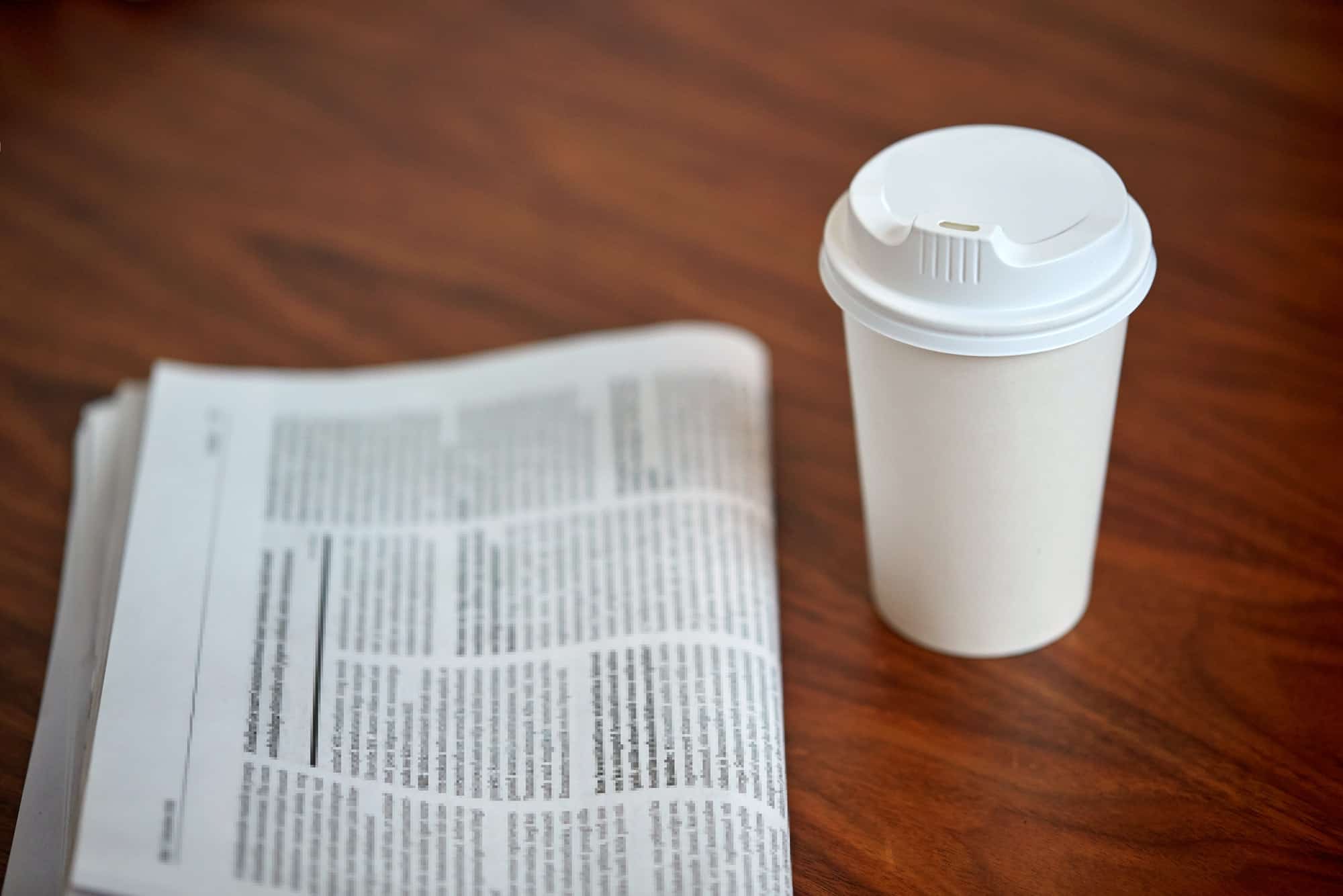 coffee drink in paper cup and newspaper on table