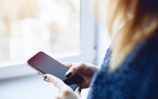 Close-up of a girl's hands with a mobile phone with a black screen.